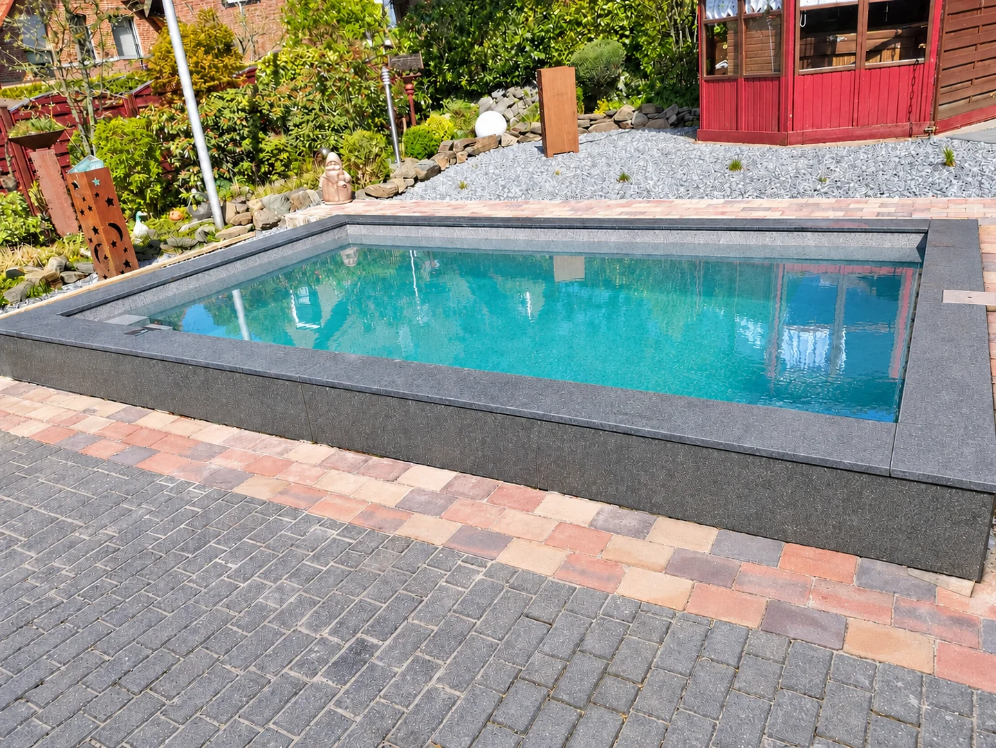 Rechteckiger Pool mit dunkler Steinumrandung und passender seitlicher Verkleidung